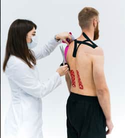 Ärztin nutzt Physio-Tape gegen ISG-Syndrom am Rücken von Patient